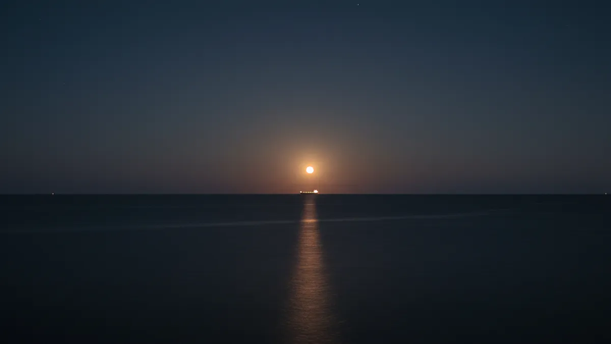 Feu de navire lointain à l'horizon de nuit, halo lumineux visible à plusieurs milles sur une mer sombre